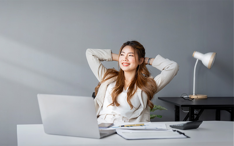 Woman leaning back in desk chair affecting tailbone pain posture.