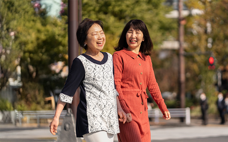 Active senior women walking outdoors comfortably without backache pain.
